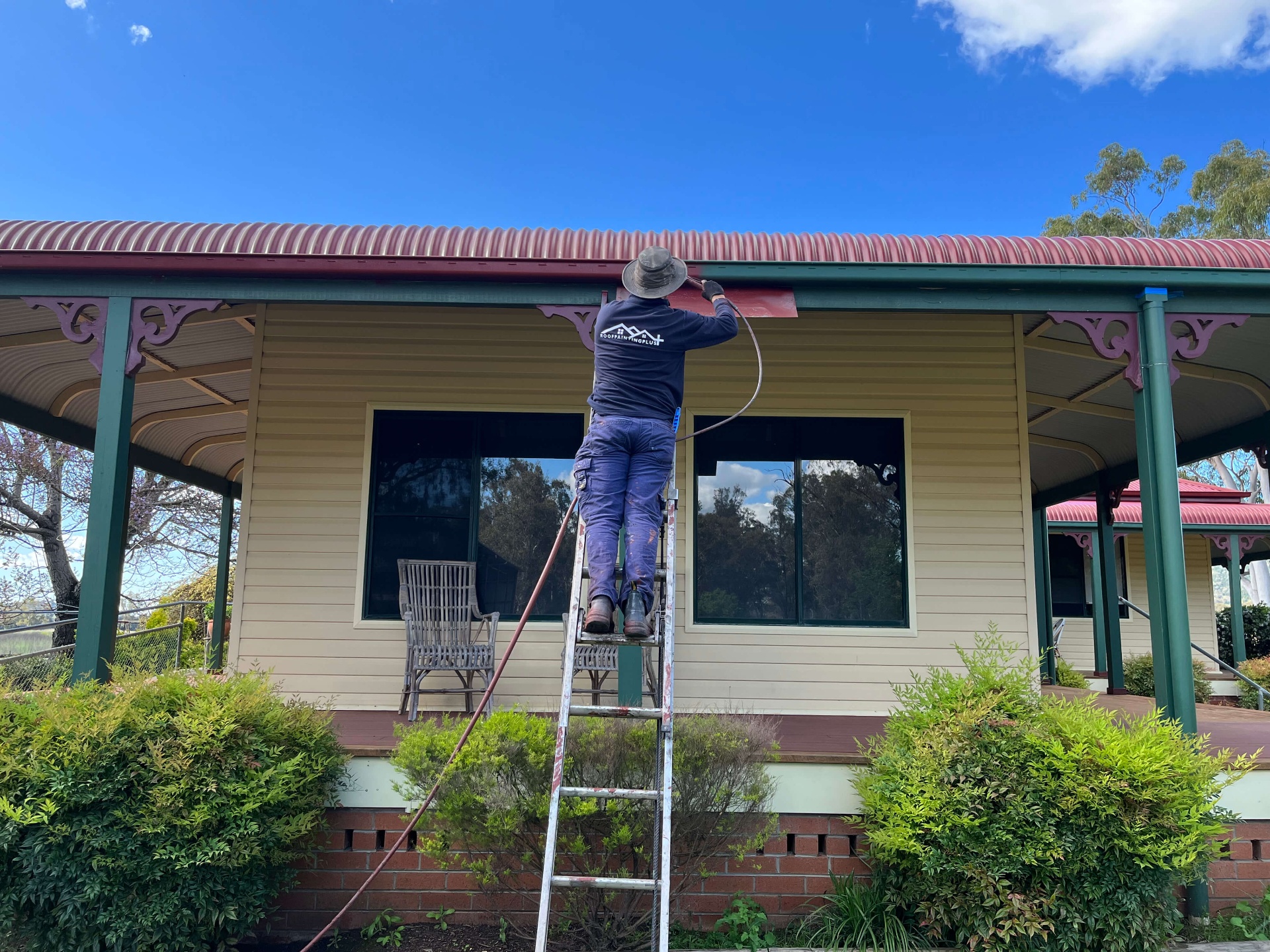 Roof Painting Plus Tradesman on a Ladder Spray Painting the Fascia of a Country Homestead