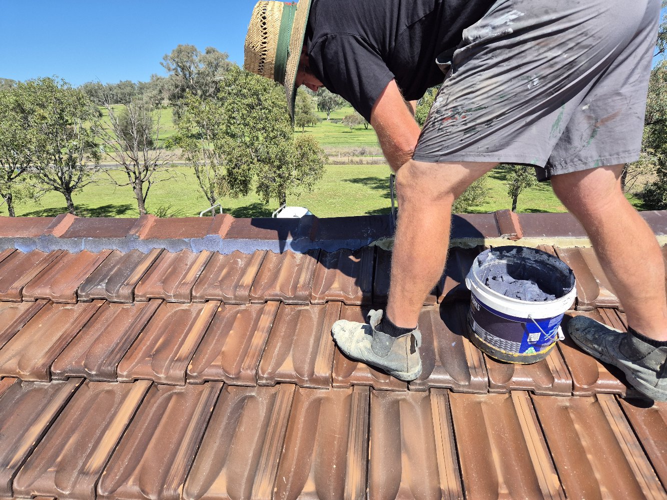 Roofer Applying Colour-Matched Flexible Pointing Compound Along a Tile Roof Ridge Line