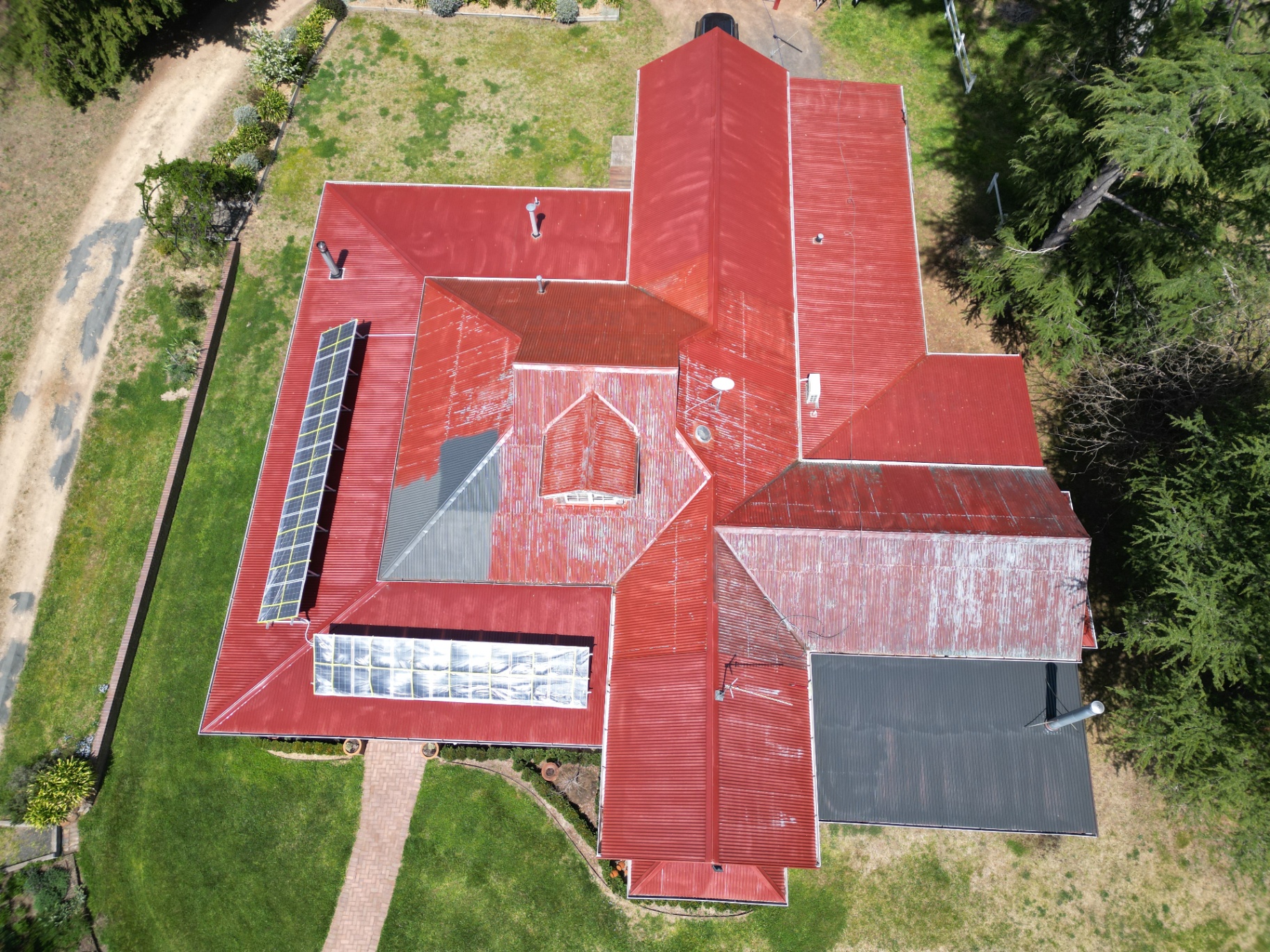 Aerial view of an Armidale farmhouse with a chalky, faded red Colorbond roof before restoration