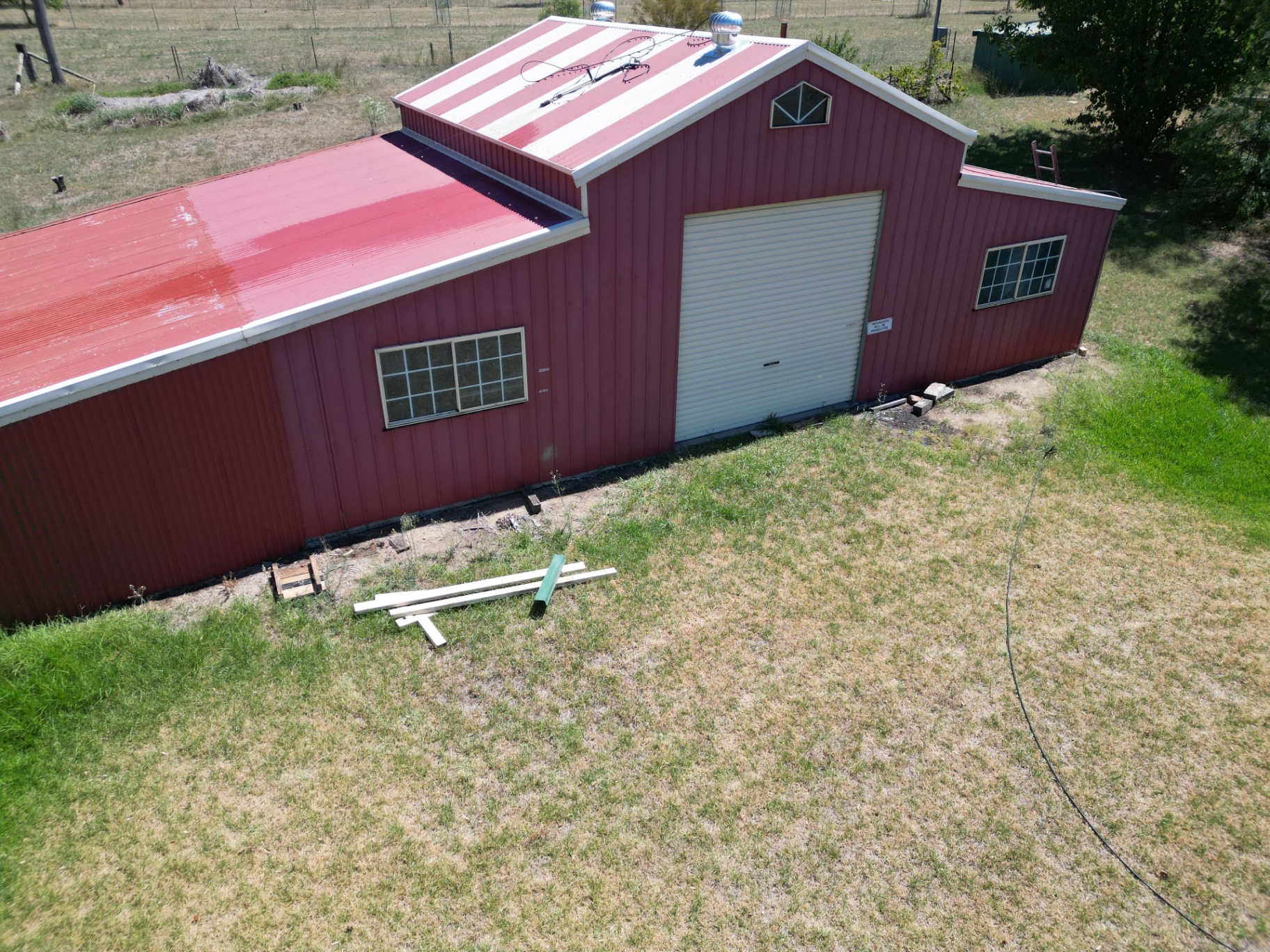 Aerial of a Faded Red Rural Shed With Patchy Roof Coating Before Restoration