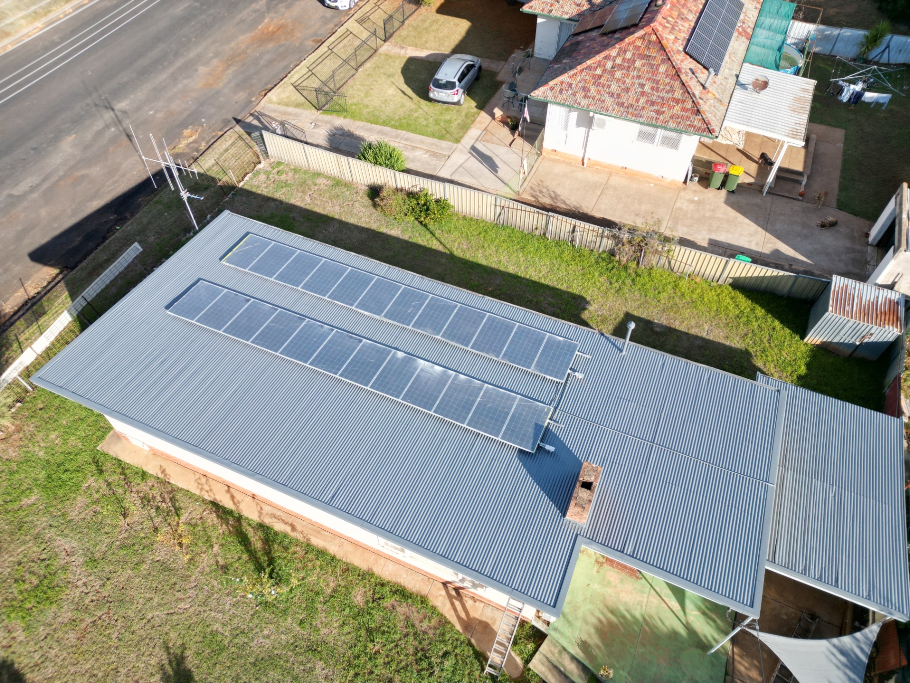 Top-Down Aerial of a Rusted Iron Roof Primed and Repainted in Basalt With Solar Panels