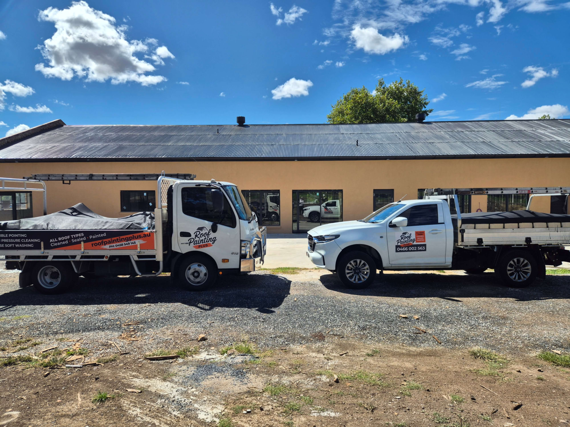 Roof Painting Plus truck and ute loaded with ladders outside a rural building