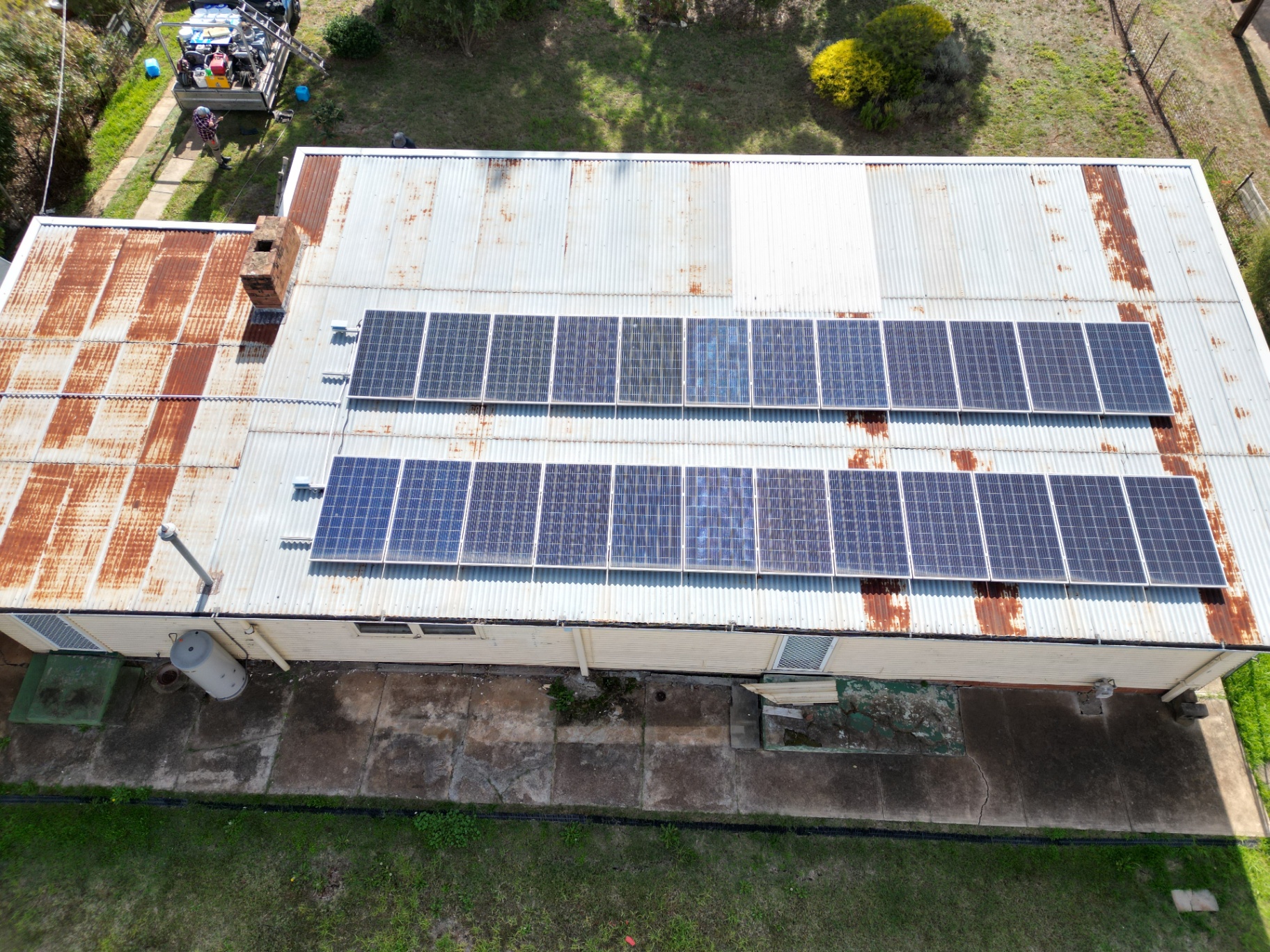 Aerial of a Heavily Rusted Corrugated Iron Roof With Solar Panels Before Restoration