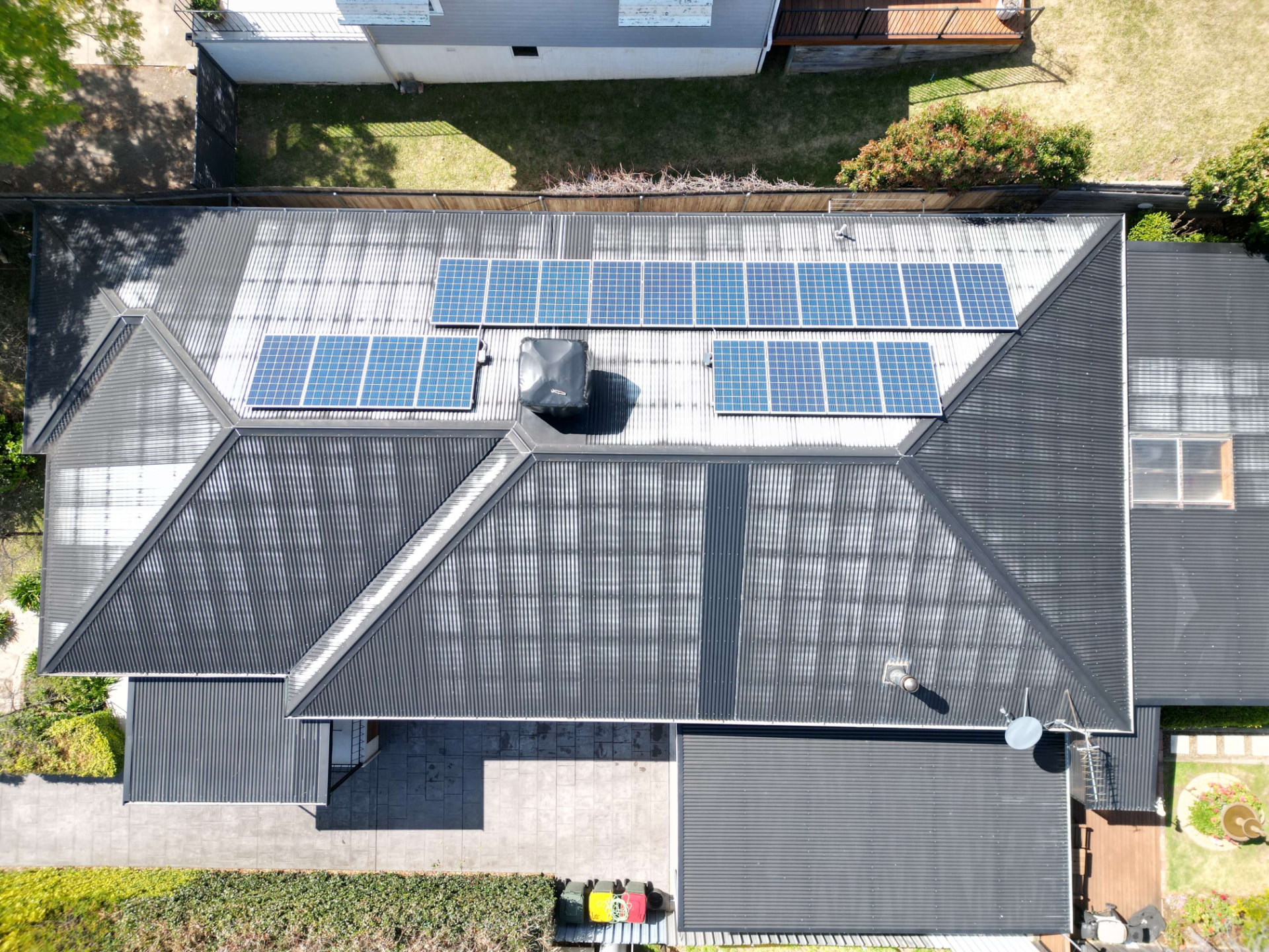 Top-Down Aerial of a Faded, Patchy Corrugated Metal Roof With Solar Panels Before Repainting
