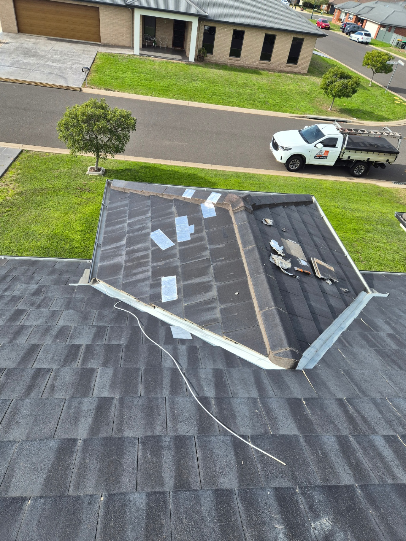 Valley Iron Replacement Underway on a Charcoal Tile Roof With the Work Truck Below