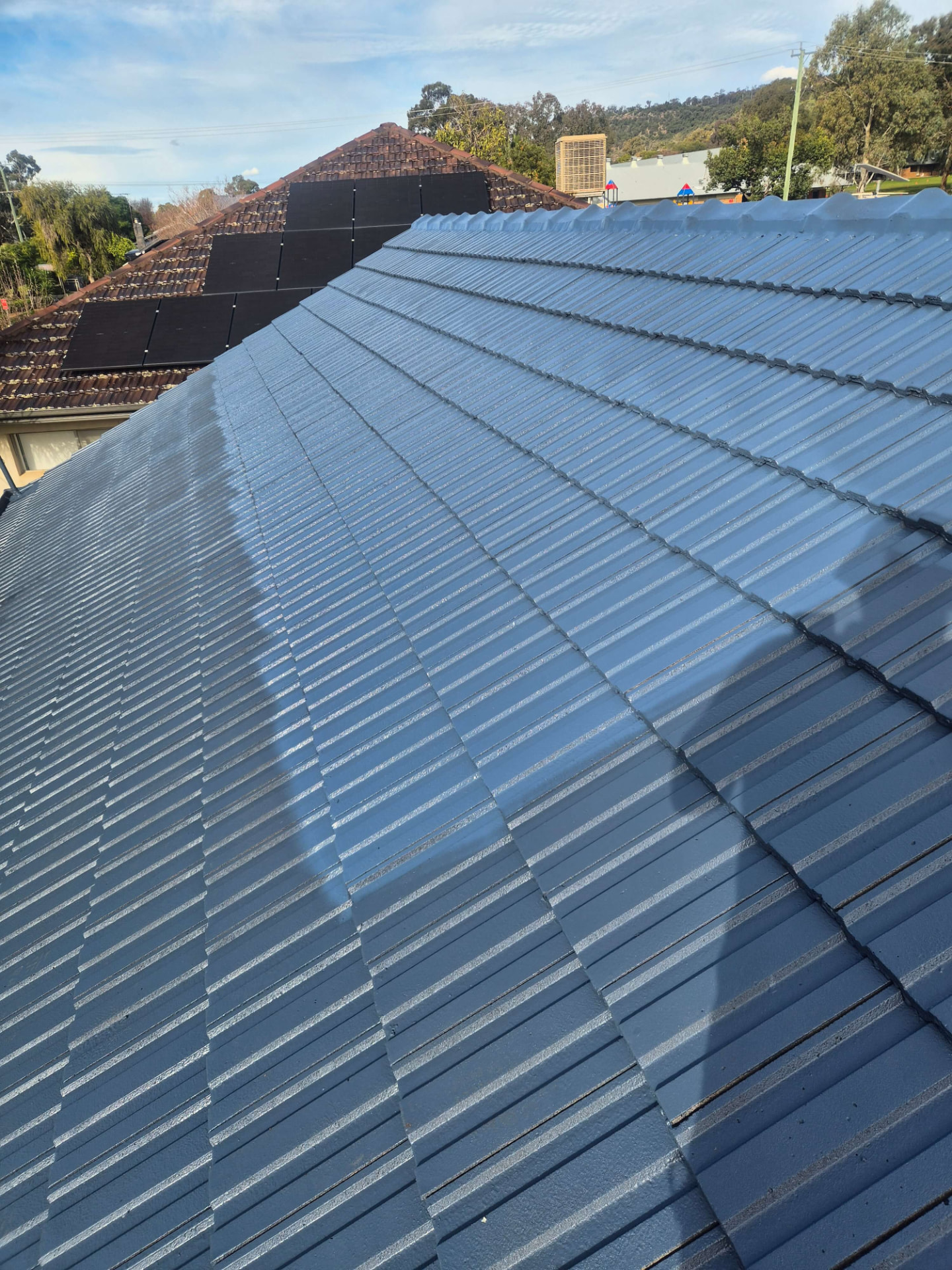 Close-Up of a Tamworth Tile Roof Freshly Restored in Deep Blue-Grey, Ridge Line Running to the Hills