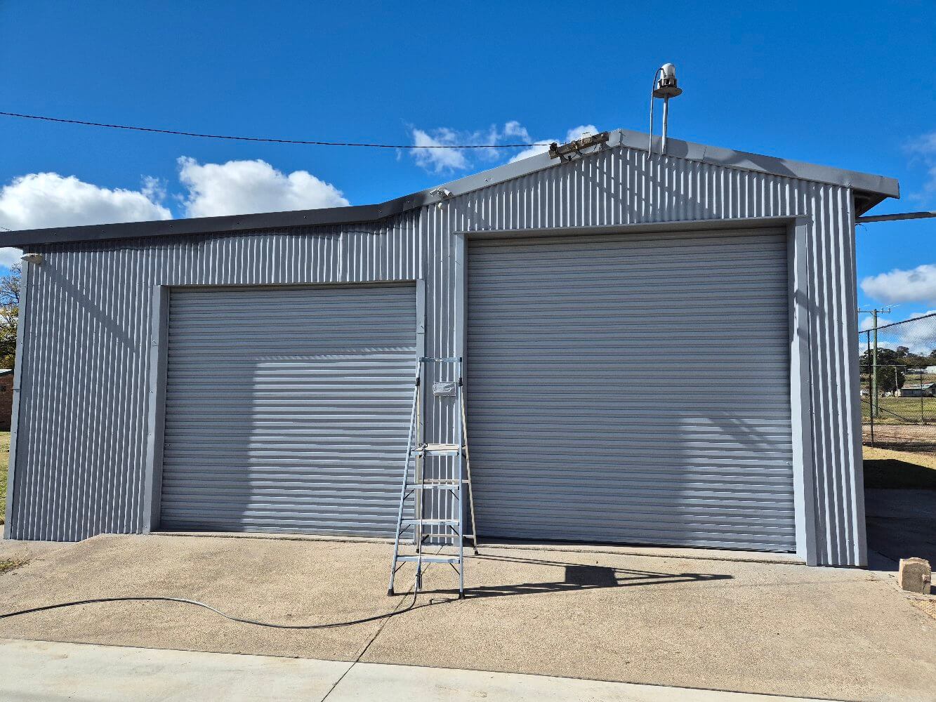 Grey Corrugated Fire Shed With Faded Cladding and Roller Doors Before Repainting