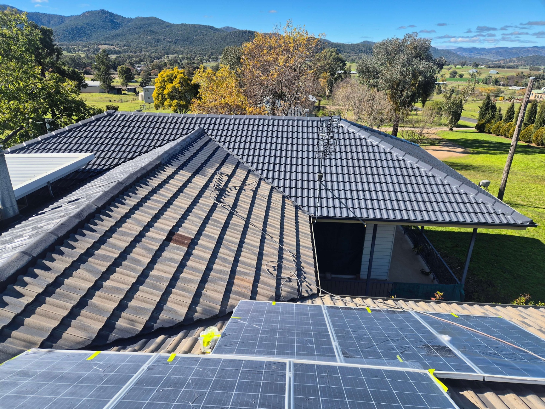 Tile Roof Half Coated in Charcoal With Solar Panels Masked Off, Peel Valley in the Background