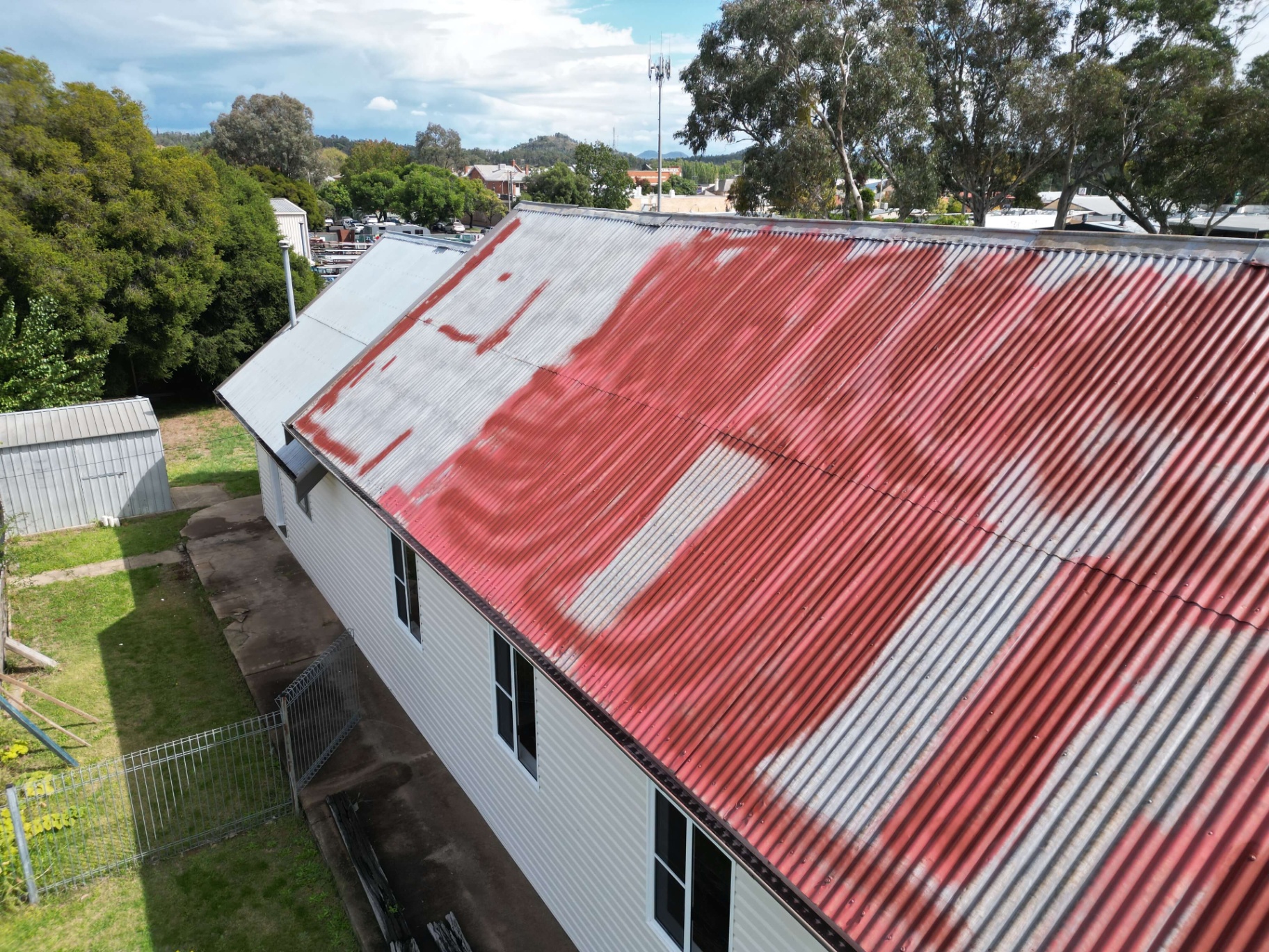 Coonabarabran corrugated metal roof with peeling red paint and bare galvanised patches before restoration