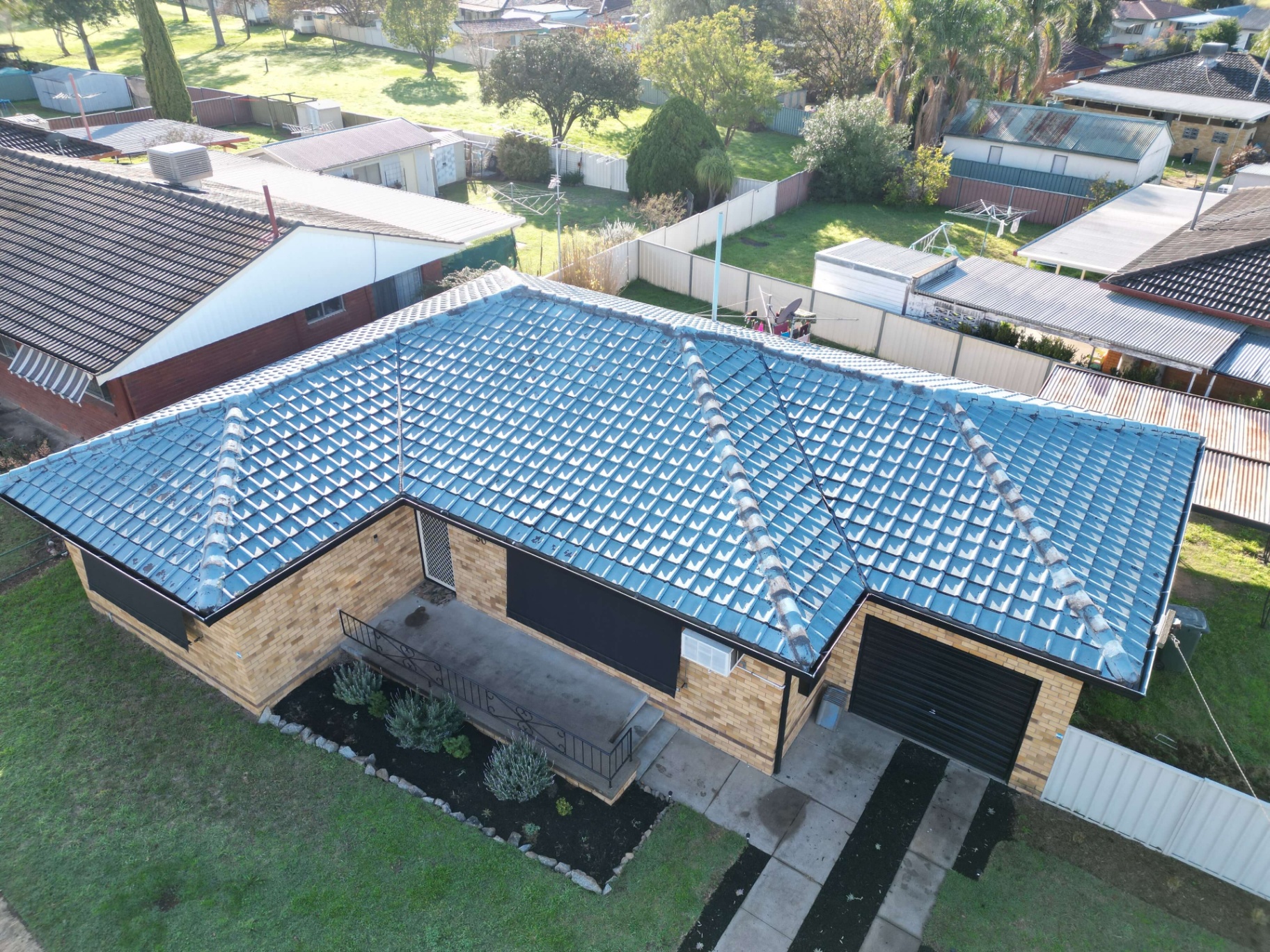 Aerial of a Brick Home With a Faded Blue Tile Roof and Worn Ridge Capping Before Restoration